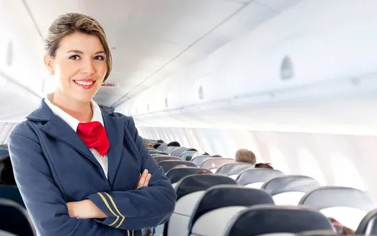Azafata sonriendo en la cabina de pasajeros de un avión