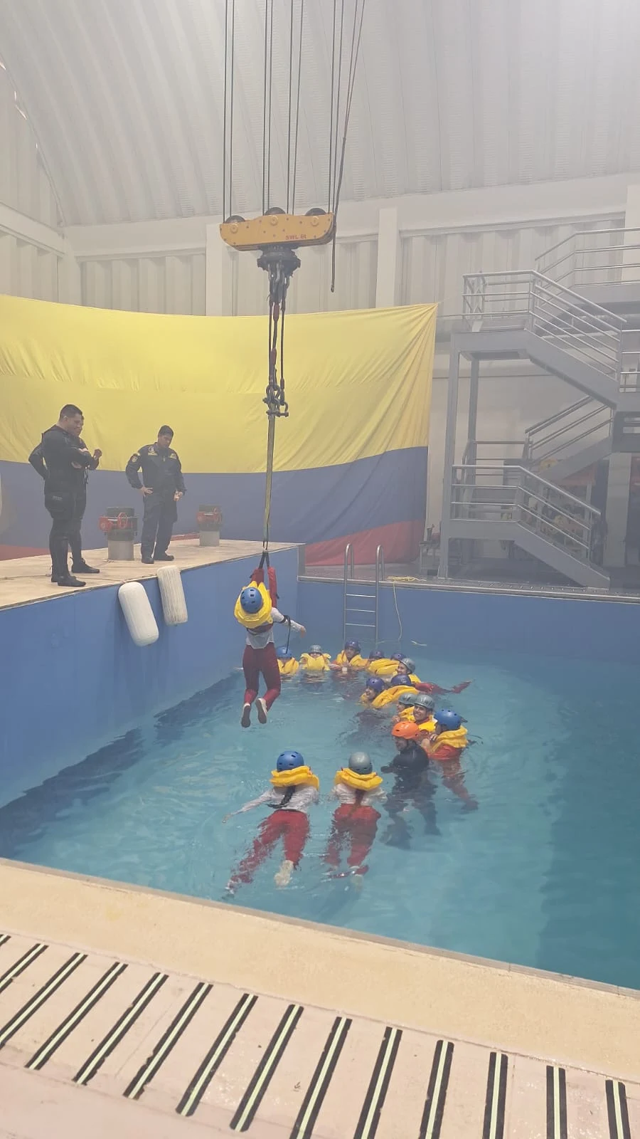 Estudiantes de ECOTET con chaleco salvavidas formando una cadena en la piscina de entrenamiento