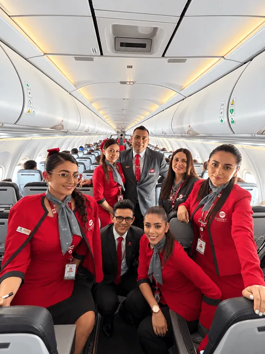 Estudiantes de ECOTET con uniforme de tripulante de cabina a bordo de un vuelo comercial durante la experiencia en vuelo