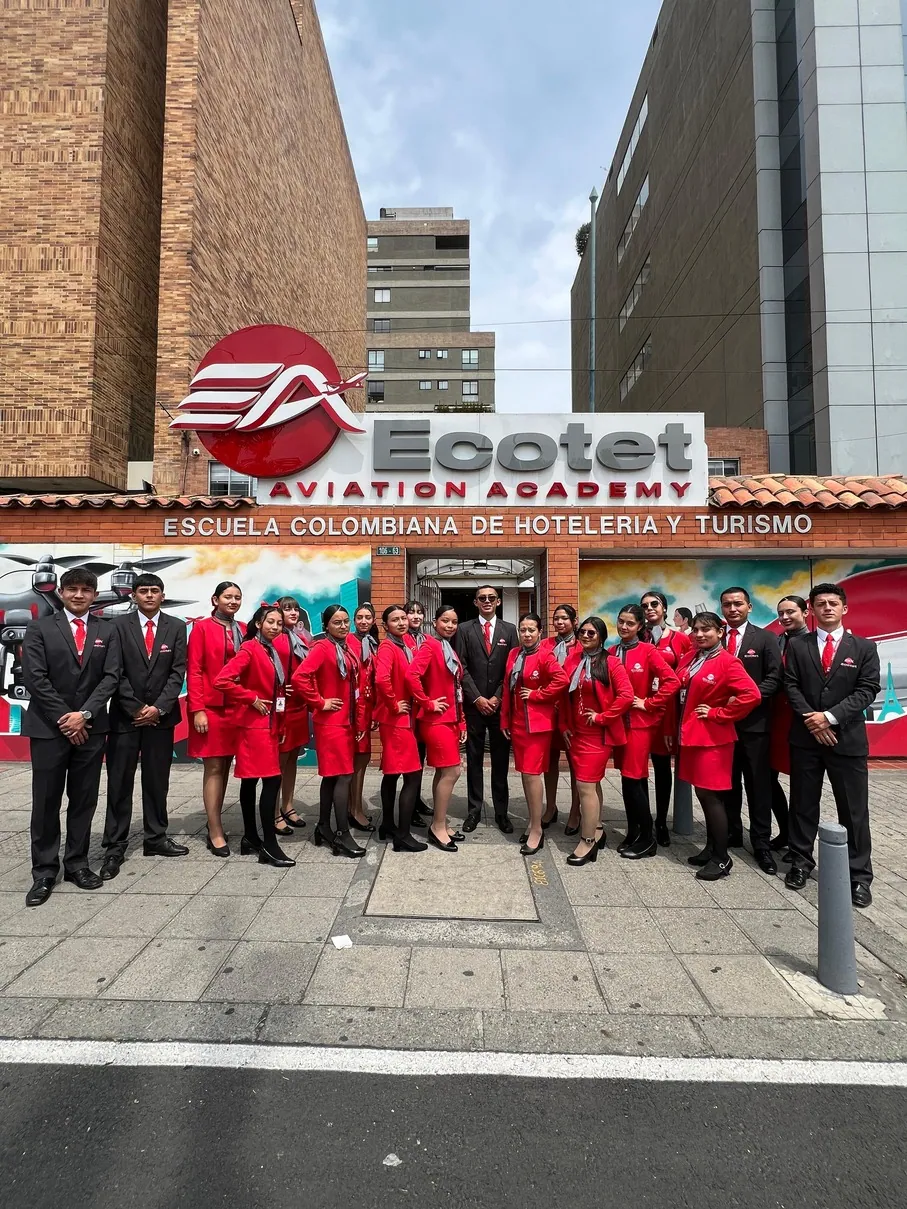 Estudiantes de ECOTET con uniforme rojo bajo el letrero de Ecotet Aviation Academy