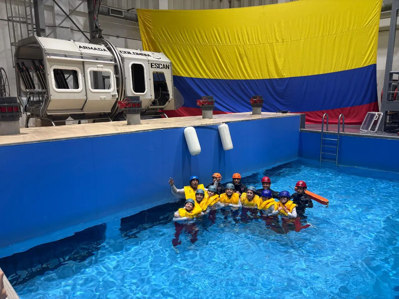 Estudiantes de ECOTET con chaleco salvavidas y casco en la piscina durante la práctica de ditching con la Armada de Colombia
