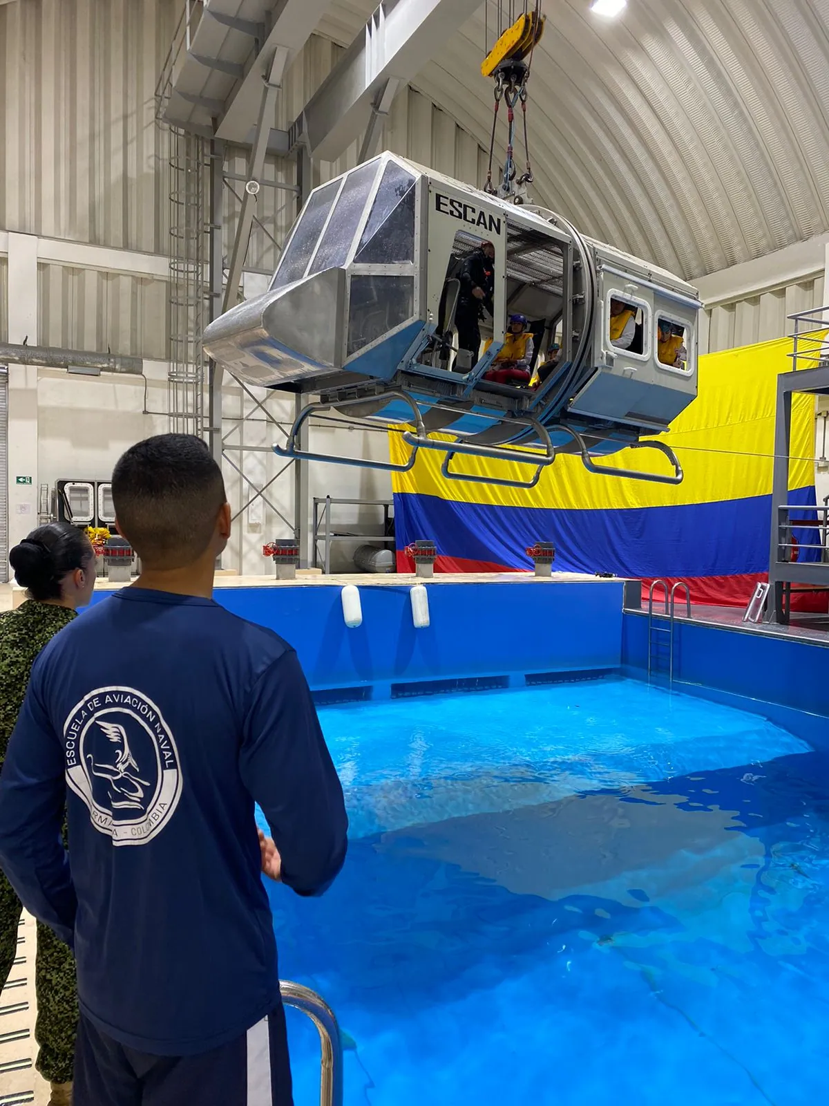 Simulador de cabina suspendido sobre la piscina durante la práctica de ditching de la carrera de azafata en ECOTET